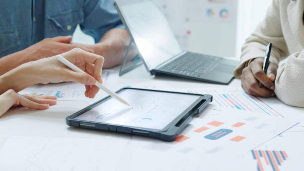 istock Close up Diverse Collaborative Business people meeting with Digital Devices computer brainstorming the financial report paperwork document analyzing data or planning strategies displays a graph or chart in a modern business technology 2183385382