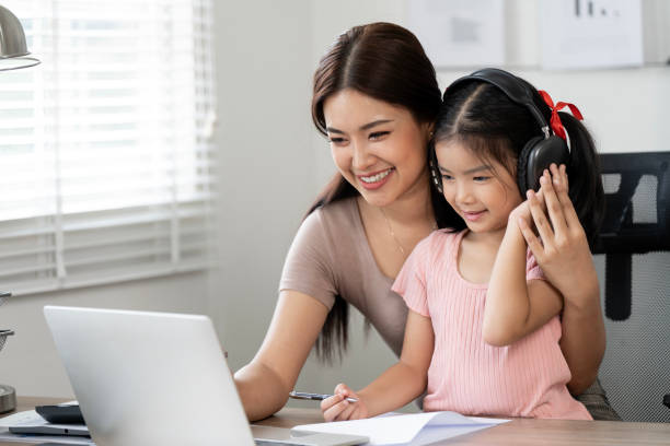 istock Asian business lady working on computer while take care her daughter at home. 2183393828