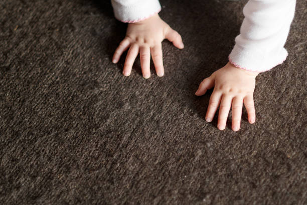 Close-up of a baby's hands while crawling on a carpeted floor