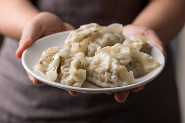 istock Steamed dumpling filled with pork and vegetables on dish holding by hand 2183399290