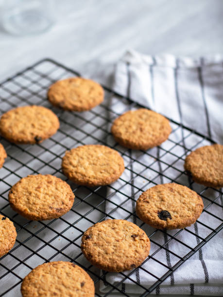 istock Freshly baked oatmeal cookies cooling on a black wire rack, with a light background and soft natural lighting. The cookies are golden brown with hints of raisins and a crispy texture, creating a cozy 2183403498