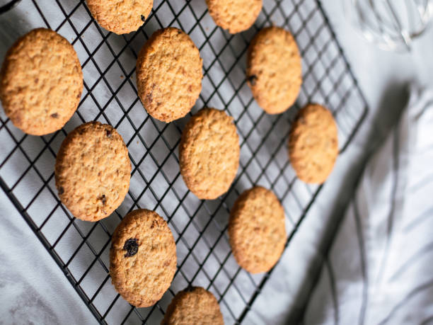 istock Freshly baked oatmeal cookies cooling on a black wire rack, with a light background and soft natural lighting. The cookies are golden brown with hints of raisins and a crispy texture, creating a cozy 2183403595
