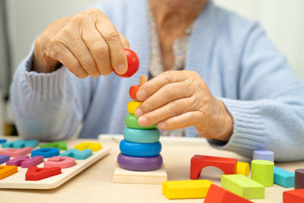 istock Alzheimer disease AD, Asian elderly woman patient suffering from dementia learn practical motor skills rehabilitation. 2183405298