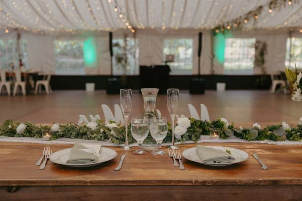 istock Long wooden table set for two with white plates, green napkins, and silverware 2183406924