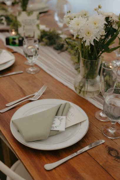 istock Place setting on a wooden table featuring a white plate, green napkin, and silverware 2183406937