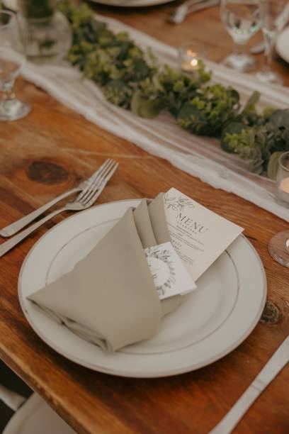 istock Place setting on a wooden table featuring a white plate, green napkin, and silverware 2183406953