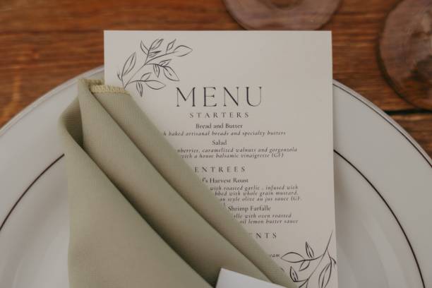 istock Minimalist wedding menu featuring a white card with black text and a green napkin. 2183409615