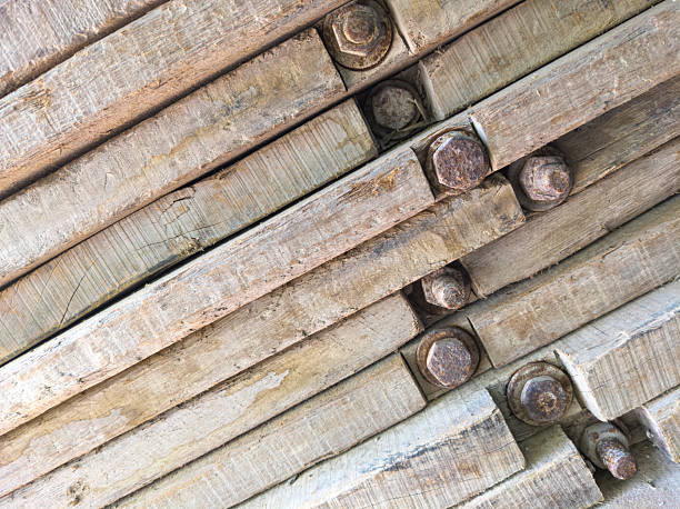 Close-up of stacked wooden planks fastened with rusty bolts. Aged texture with natural grain and weathered surface. Suitable for backgrounds, carpentry, construction, or vintage industrial themes.