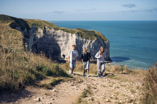 istock Teenagers hiking on a rocky path atop Etretat cliffs. 2183411024