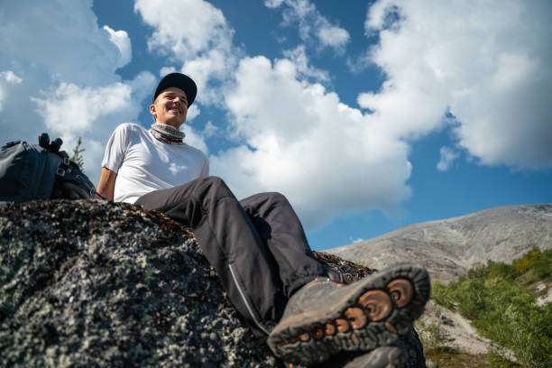 istock Young Man Relaxing on Mountain Rock Under Blue Sky 2183415381