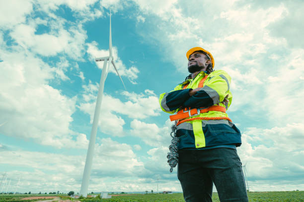 istock Smart confident African black engineer technician male worker service maintenance wind turbine at Wind Turbines electricity generator farm field outdoors. 2183419662