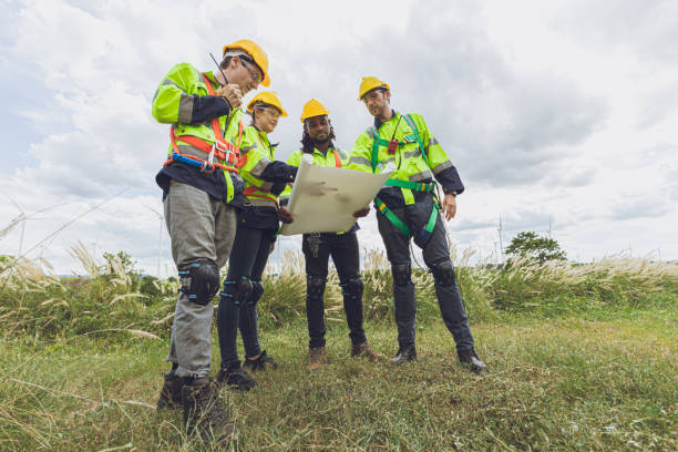 istock Group of Engineer team workers looking floor plan together at Wind Turbines working service planning at wind electricity generator farm field. 2183419664