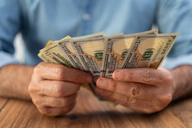 istock Man company accountant holds dollar banknotes counting necessary quantity for paying services 2183425812