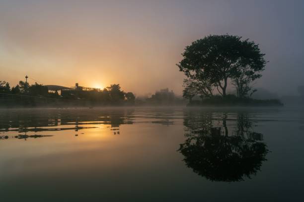 istock Serene sunrise over a misty lake with tree reflection. 2183426718