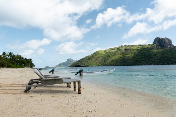 istock On a tropical island beach, brown deck chairs are set up for sunbathing, with a blue channel and distant coral as the backdrop 2183433389