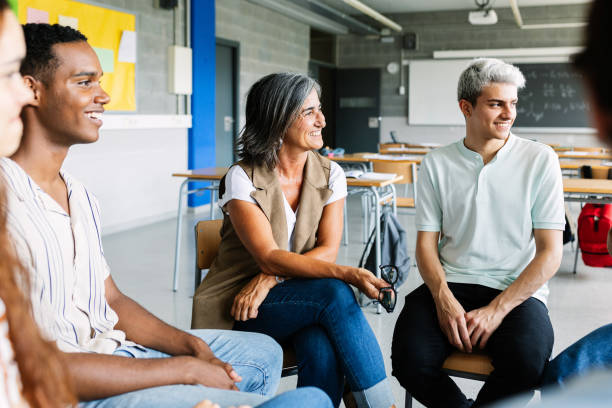 istock Young high school students talking with teacher in focus group therapy session 2183443265