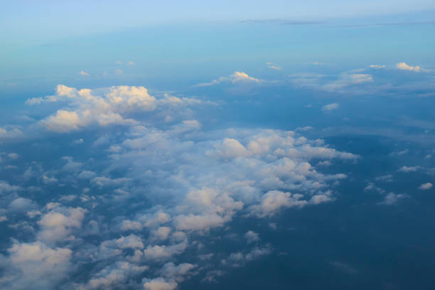 istock Fluffy white clouds covering earth from airplane window at sunset 2183444336