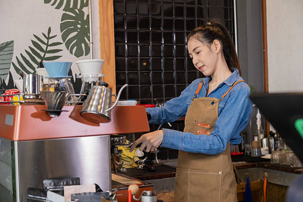 istock Young attractive Asian barista female using professional coffee machine making hot espresso and pouring coffee to mug in cozy cafe, small businesses start up for young people lifestyle concept 2183444505