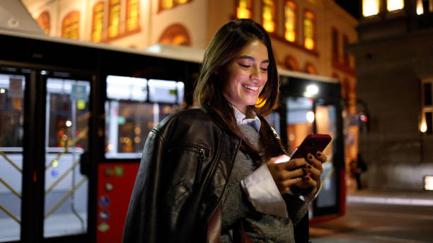 istock Woman walking through the city lights, using smartphone with a smile 2183447352