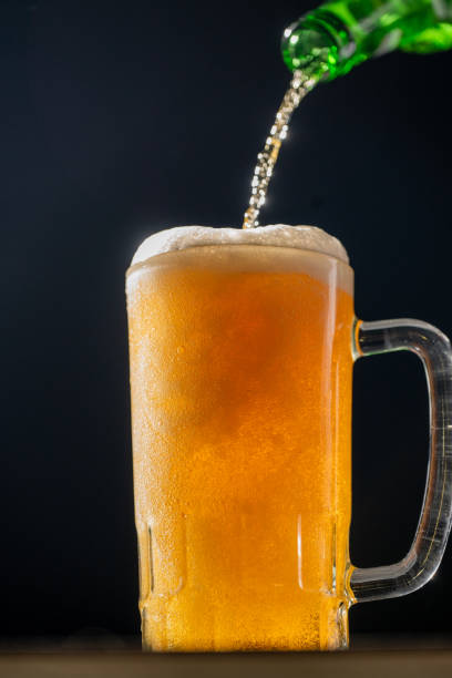 istock A bright and refreshing beer is being poured into a cold glass mug. The golden liquid, illuminated by a dark background, perfectly captures the celebratory essence of Beer Fest. 2183449410
