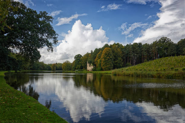 The ruined abbey beside the lake at Painshill Park in Cobham Surrey England UK