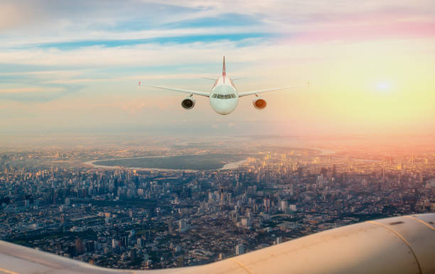 istock Airplane Flying Over City at Sunset 2183454822