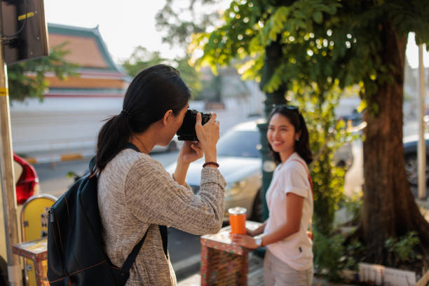 Thai man takes a photograph with a camera of his beautiful girlfriend on the historic streets of Bangkok.
