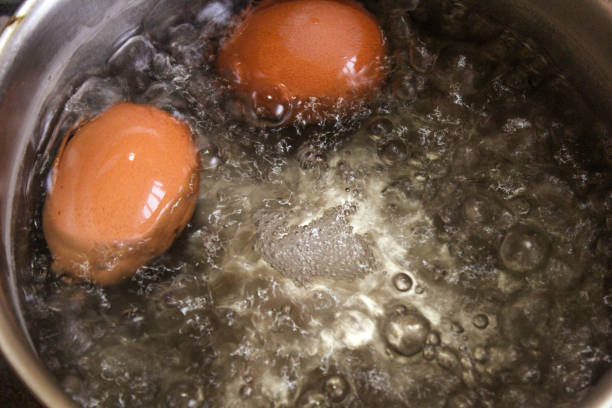 istock two brown chicken eggs are boiled in a saucepan in water with foam 2183459445