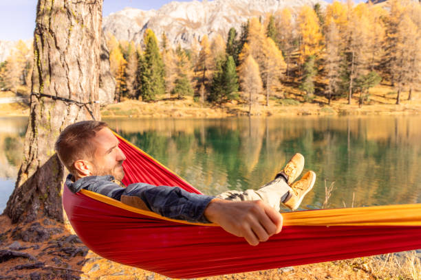 istock Man Relaxing in a Hammock by Scenic Mountain Lake in Autumn 2183459631