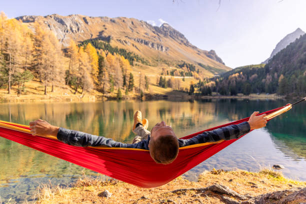 istock Man Relaxing in a Hammock by Tranquil Mountain Lake in Autumn 2183459674