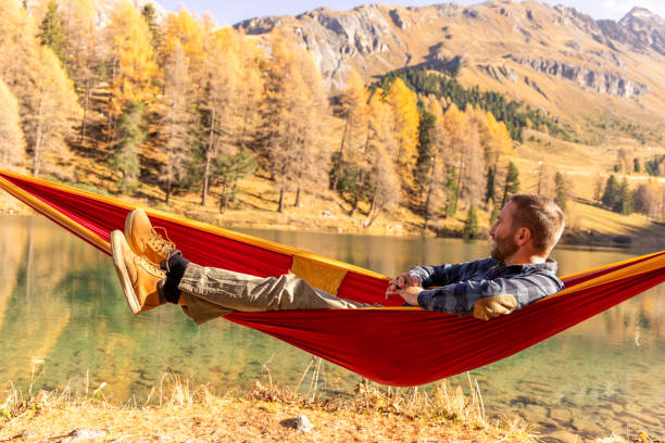 istock Man Relaxing in Hammock Overlooking Lake in Autumn Landscape 2183459723