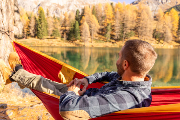 istock Man Relaxing in Hammock Overlooking Lake in Autumn Landscape 2183459742