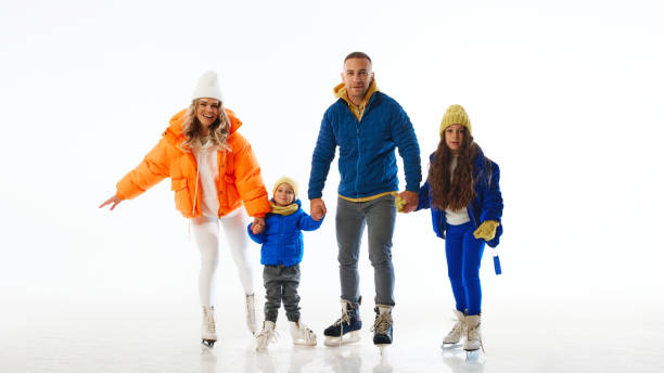 istock Happy family holds hands while ice skating, showcasing their togetherness and joy during winter adventures against white studio background. 2183460680
