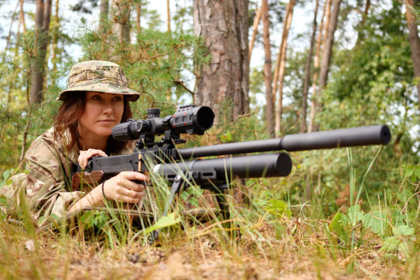 istock A skilled marksman in camouflage gear carefully aims with a sniper rifle while lying in a forested area during daytime 2183463467