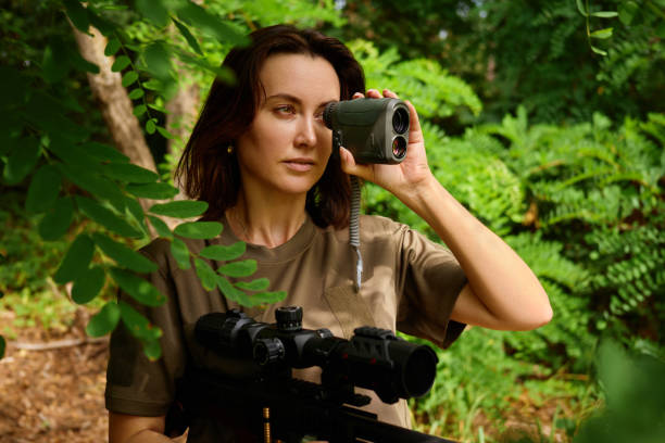 istock A woman using a rangefinder in a lush green forest while observing wildlife during a sunny afternoon 2183463498