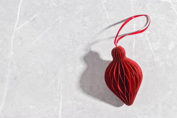 istock One Red Christmas paper bauble as flashlight on marble grey table, Scandinavian Christmas honeycomb ornaments. New year paper decor, modern xmas decoration, minimal winter holiday, copyspace 2183466566