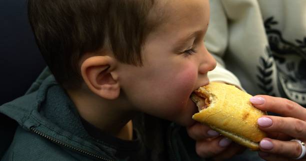 small child lovingly embraces a bag of groceries with freshly baked bread, smiling softly, holding the bread tightly to his chest.
