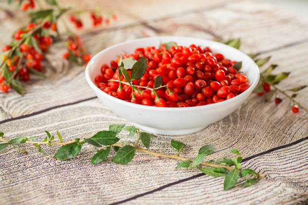 fresh ripe red goji berries in a bowl on a wooden table .