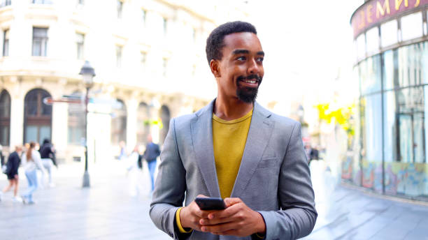 istock Black man walking down a street, texting on his smartphone 2183481504
