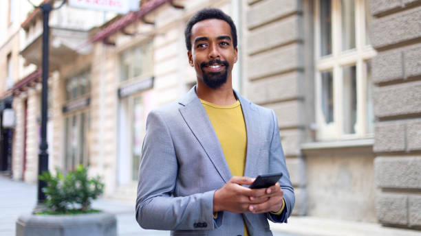 istock Black man walking down a street, texting on his smartphone 2183481746