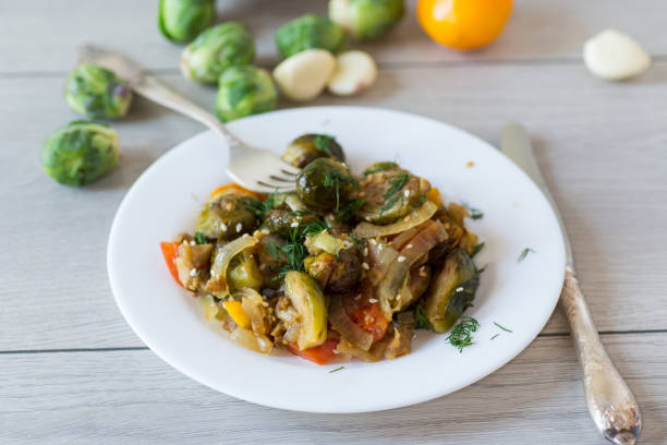istock Brussel sprouts cooked with vegetables and spices, on a wooden table 2183481935