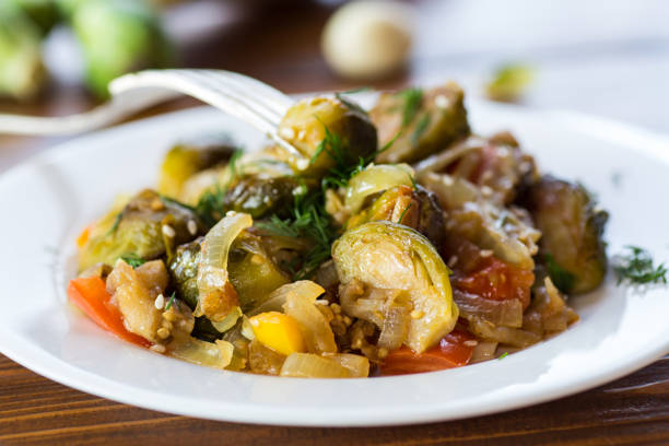 istock Brussel sprouts cooked with vegetables and spices, on a wooden table 2183481995