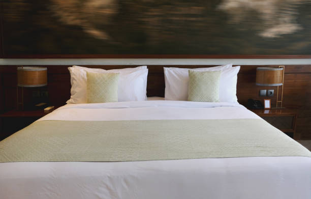 Close-up shot of  Cozy Green Pastel Pillow and Bed Runner in a Modern Hotel Room.Concept: hotel bed, comfy pillow, green accent pillow, loose pillow, bed runner, clean bed sheets, modern room design, cozy elegance, relaxation, contemporary decor, restful space, hospitality, welcoming ambiance, minimalist bedding, fresh linens, neutral tones, stylish comfort