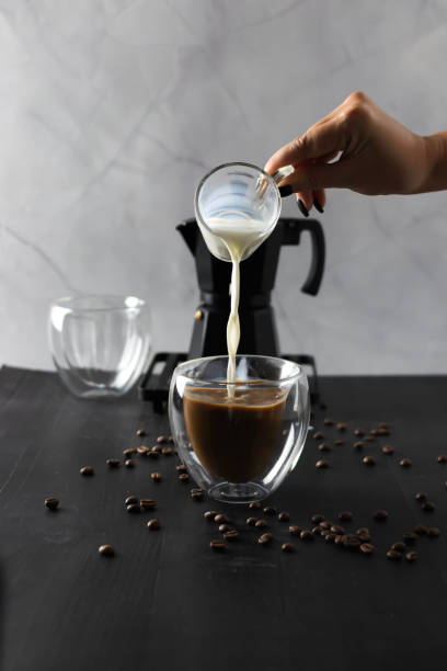 istock Black coffee is poured into a cup, on a black background. pour milk into coffee 2183488754