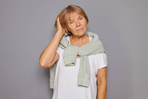 istock Senior Caucasian assertive focused female displaying confidence and calm looked with concentration touching her head and hair isolated over gray background 2183489349