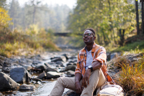 Man resting by a river in the forest