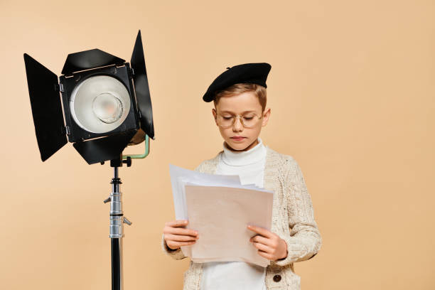 istock Adorable little boy dressed as a vintage character sits reading scripts by a studio light 2183499150
