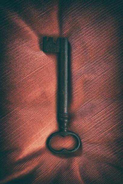 istock Old key resting on red velvet fabric 2183499534