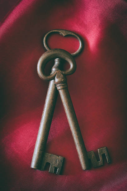 Two ornate antique keys are resting on a luxurious red velvet fabric, suggesting mystery, history, and secrecy