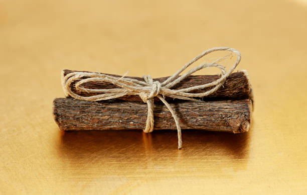 istock Dried licorice roots tied with string on a golden background 2183499649